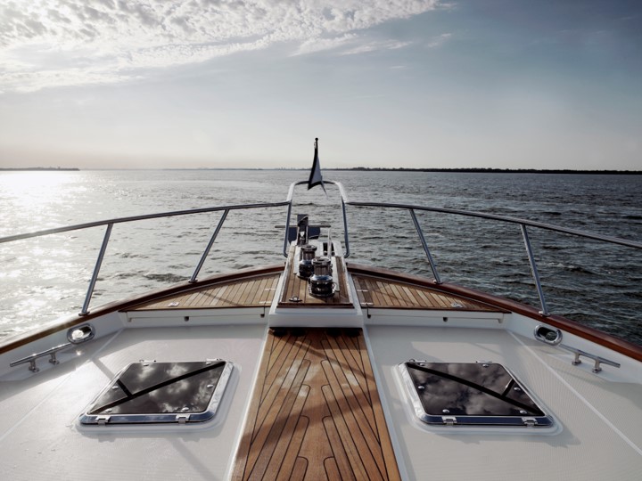 An image of a front tip of a boat looking towards the sea horizon